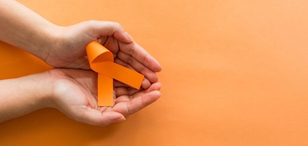conciencia-leucemia-liston Manos sosteniendo listón naranja por concientización de leucemia