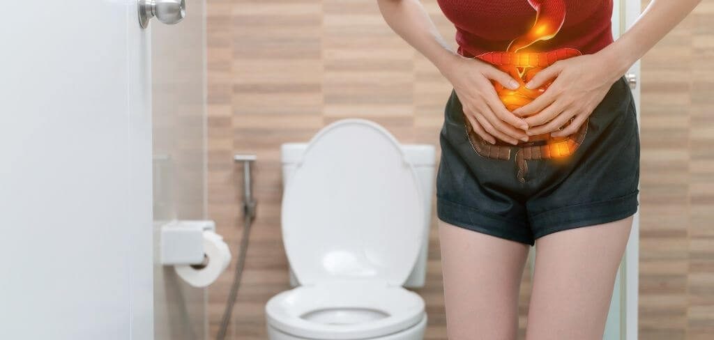 dolor-abdominal-diarrea Persona con dolor estomacal en el baño por diarrea.