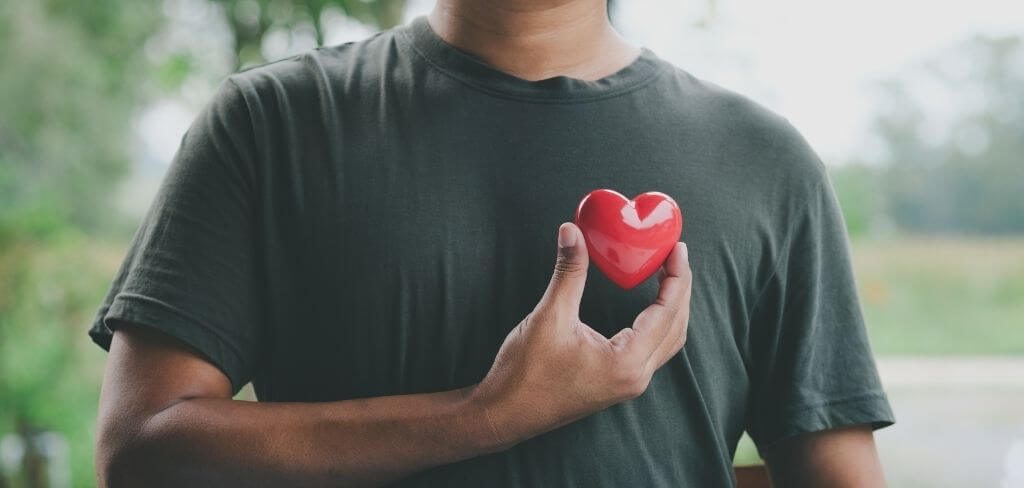 salud-cardiaca-prevencion-lab Hombre con camisa verde sosteniendo un corazón, en representación de la salud del corazón.
