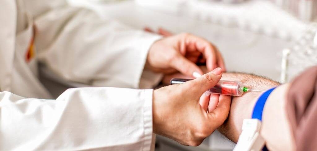 toma-muestra-sangre-profesional-lab Toma de muestra sanguínea por químico con bata blanca.